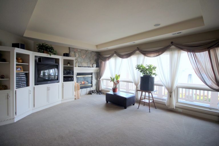 living area of home with TV, white cabinets, light coming through windows